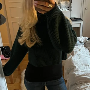 Mörkgrön stickad croppad tröja - Superfin mörkgrön stickad croppad tröja med långa ärmar. Jättesnyggt med ett tight linne under men går även att ha utan om man gillar det🥰