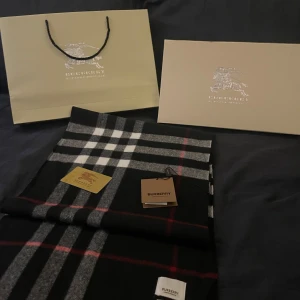 Burberry halsduk - Säljer nu denna riktigt snygga Burberry halsduken. | Deb är i riktigt bra skick 9/10. Och det fins inga tecken på att den är använd. | Det som ingår är en påse, låda, Burberry kort och lappen som satt fast på halsduken när den köptes. Och man får självklart med halsduken också.. Allt som man får med är med på bilderna. | Det är bara att höra av sig om man har några frågor eller funderingar🧣🧣🧣