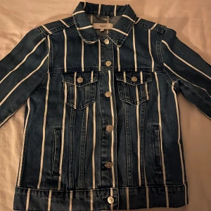 Randig jeansjacka  - Snygg jeansjacka från Next med vertikala vita ränder. Jackan har knappar framtill och två bröstfickor med knappstängning. Storlek M, men skulle säga att den passar mer som Xs eller S. 