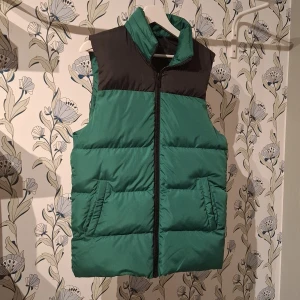 Grön pufferväst från asos  - Grön pufferväst från asos i storlek 2XS fast den passar även storlek XS & S. Västen har en dragkedja framtill och två praktiska fickor. Perfekt för kyligare dagar.