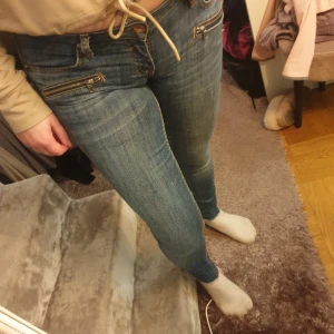 Blå skinny jeans med dragkedjor - Snygga blå skinny jeans med coola dragkedjor framtill. De har en tight passform och är perfekta för en trendig look. Klassisk femficksdesign med två bakfickor och knappstängning. Från river island storlek 8. Jätte sköna o stretchiga. Tror det ska vara ankel längd, men passar perfekt på mig som är 160. Använda fåtal gånger.