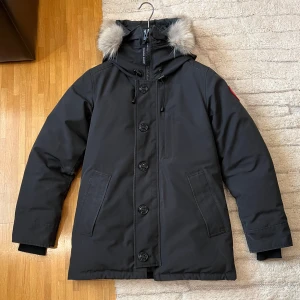 Canada Goose Chateau Fusionfit - S - Säljer en svart parkajacka från Canada Goose med pälsdetalj på huvan. Chateau heter modellen. Inga hål eller slitningar på jackan, fint skick. Nyligen kemtvättad inför försäljning via NK i Stockholm. Skickas i original kartong som den kom i när jag köpte den från Canada Goose egna hemsida. Kvitto på jackan finns dessutom.  Perfekt för kyliga dagar!