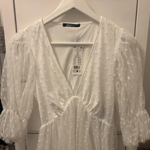Vit prickig klänning från Gina Tricot - Klänning  från Gina Tricot med prickigt mönster och v-ringning. Perfekt för studenten! Nypris 700 kr, aldrig använd. Alltså nyskick. 