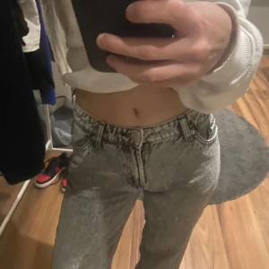 Grå jeans med låg midja - Snygga grå jeans med låg midja och klassisk femficksdesign. Perfekta för en avslappnad stil med en croppad tröja eller hoodie. De har en straight passform som ger en tidlös look.