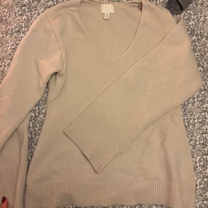 Beige stickad tröja från H&M - Säljer en stilren beige stickad tröja från H&M. Tröjan har en v-ringad hals och långa ärmar med ribbade skurna muddar. Strl s 💕
