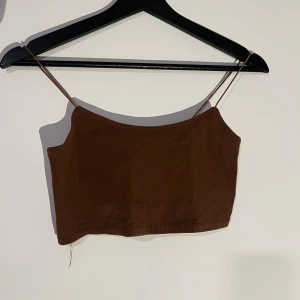 Brun croppad tubtopp - Snygg brun croppad tubtopp med smala axelband. Perfekt för varma sommardagar eller som ett lager under en jacka. Enkel och stilren design som passar till många olika outfits.