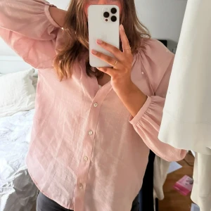 Rosa blus från Zara - Säljer en söt rosa blus från Zara med långa ärmar och knappar framtill. Blusen har en avslappnad passform och är perfekt för en stilren look. Den är gjord i ett lätt och luftigt material som passar bra till både vardag och fest!
