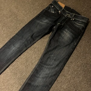 Dondup jeans  - Snygga mörkblå dondup jeans med klassisk femficksdesign och kontrastsömmar. De har en slim passform och är perfekta för en avslappnad stil. Byxorna har en knappgylf och är tillverkade i slitstarkt denim. 