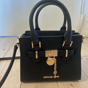 Micheal kors väska - Liten svart väska med guldiga detaljer från Michael kors. Köpt på i USA. Aldrig använt så i väldigt bra skick. Justerbart band 
