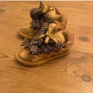 Lanvin curbs  - Snygga beige sneakers från Lanvin med unika, breda snören i svartvitt mönster. Skorna har en stilren design med detaljer i mocka och en bekväm sula. Perfekta för en trendig look. Dem är självklart äkta!!