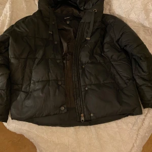 Svart pufferjacka från Vero Moda💗 - Säljer en svart pufferjacka från Vero Moda. Jackan har en dragkedja och knappar framtill samt en luva. Det är en nyans av svart grön i vissa ljus 