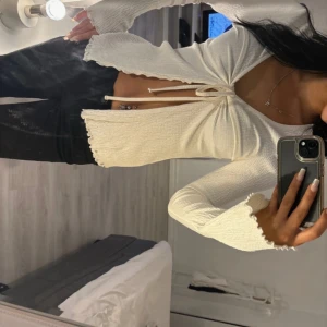 Vit ribbad knytblus - Snygg vit ribbad blus med knytning framtill. Blusen har långa ärmar och en stilren design som passar perfekt till både vardag och fest. Perfekt för att skapa en chic look.