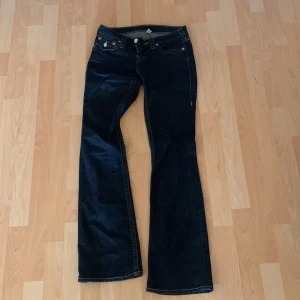Mörkblå bootcut jeans från True Religion - Säljer ett par snygga mörkblå bootcut jeans från True Religion. De har klassiska femficksdetaljer och kontrastsömmar. Perfekta för en avslappnad stil med en touch av retro. Jag säljer dessa då de är för små för mig. Använt ca 2-3 gånger