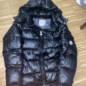 Svart pufferjacka från Moncler - Säljer en snygg svart pufferjacka från Moncler. Jackan är i storlek M men passar mest som S. Jackan har en quiltad design med dragkedja och en praktisk huva. Perfekt för kyliga dagar och håller dig varm med stil. Loggan går att scanna också. Priset kan diskuteras:)