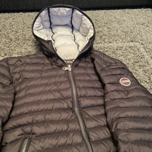 KOM MED PRIS!! Svart pufferjacka från Colmar ny Pris 2799kr används fåtal gånger! - Snygg svart pufferjacka från Colmar med dragkedja och huva. Jackan har ett quiltat mönster och är perfekt för kyligare dagar. Den har en logotyp på bröstet och är helfodrad i vitt.