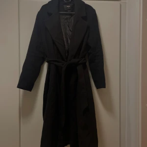 Svart kappa  - Säljer en svart kappa från bikbok. Har använt några säsonger men är fortfarande super fin!! Har dock fått slitage på en av ”innerfickorna” (se bild) men annars är den som ny! Perfekt nu till vintern✨🫶🏻