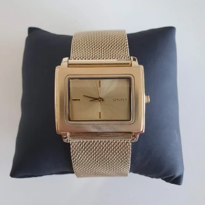 Klocka DKNY  - Klocka från märket DKNY. Guld färg. Oanvänd och är i god skick, har inga defekter. Extra länk följer med.