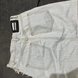  Kjol  - Snygg denimkjol med fransar i ljusblå färg. Kjolen har en hög midja och en rak passform. Den är perfekt för både vardag och fest.