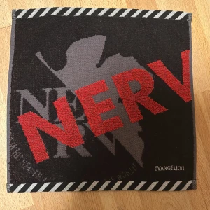Officiell Evangelion Handuk NGE - Licenserad Nerv NGE handduk köpt i Tokyo. Fett cool design, dessa brukar användas som svetthanddukar i Japan men de kan användas som vanlig handduk också.
