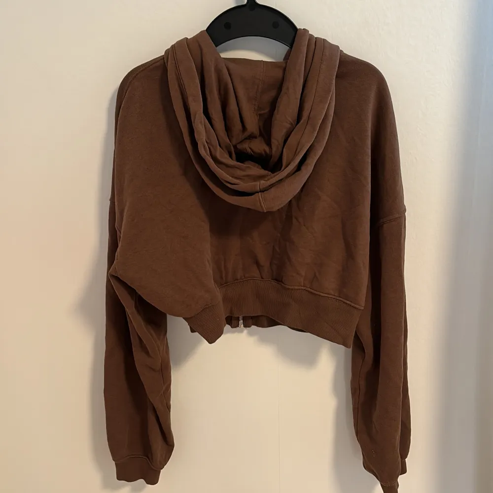 En brun croppad luvtröja från H&M Divided. Den har en dragkedja framtill och fickor. Nyskick!. Neuletakit & Villapaidat.