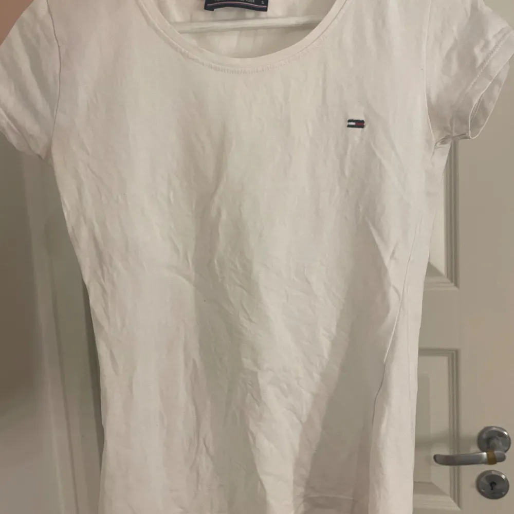 Vit T-shirt med ett litet Tommy hilfiger märke på, den är i en tightare passform💞 den passar xs-s. T-shirts.