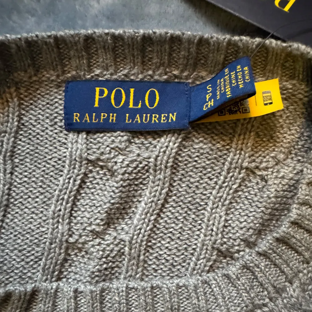 Säljer en superfin beige stickad tröja från Polo Ralph Lauren. Den har ett klassiskt flätmönster och är perfekt för både höst och vinter. Tröjan är långärmad och har en normal passform. Den är i nyskick och redo att hålla dig varm och stilren!. Tröjor & Koftor.