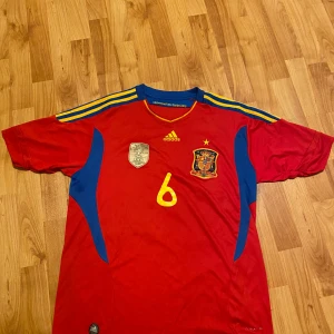 Iniesta VM 2010 - Tja! Säljer denna galet snygga och väldigt sällsynta Spanien tröjan från vm 2010 med iniesta på ryggen! Tröjan är i 7/10 skick, det finns några väldigt små hål som man kan se på bild 5, därav priset. Bara att skriva om ni har några andra frågor!😁