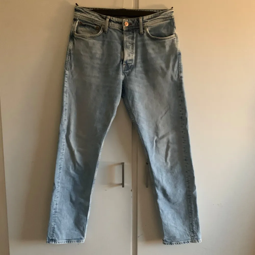 Säljer ett par ljusblå jeans från Jack & Jones i modellen Loose/Chris. De har en avslappnad passform och är perfekta för en casual look. Jeansen har en klassisk femficksdesign och stängs med en knapp och dragkedja. Perfekta för både vår och sommar!. Jeans & Byxor.