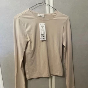 Långarmad topp - En beige långarmad topp i tunt material. 