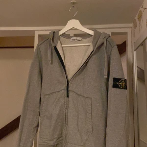 Grå hoodie från Stone Island - Säljer en snygg grå zip hoodie från Stone Island. Anledningen är att jag har vuxit ur den. Pris går att diskutera.