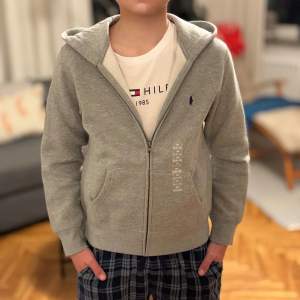 Helt ny oanvänd grå Poli Ralph Lauren Zip hoodie. Inköpt i USA, säljer den då den var för liten för min son. Med fulla tags/lappar. Den går annars att köpa på Kids Brandstore för 1.195:-