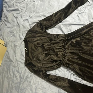 Svart glittrig klänning - Säljer en superfin glittrig svart romper som glittrar jätte fint.Den har långa ärmar och en smickrande passform som är perfekt för festliga tillfällen. Materialet känns lyxigt och klänningen har en elastisk midja för extra komfort. Aldrig använt. 