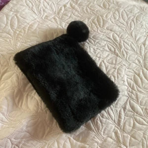 Svart pälsväska med pompom - Säljer en supermjuk och fluffig svart pälsväska med en söt pompom-detalj. Perfekt för att ge din outfit en mysig touch! Väskan har en dragkedja för säker förvaring av dina saker. Den är liten och smidig, perfekt för en utekväll eller när du bara vill ha med det viktigaste.