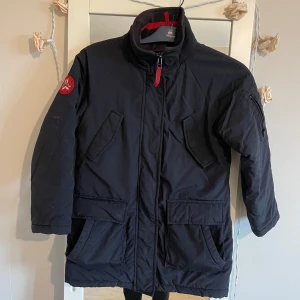 Svart vinterjacka från Dcate - Säljer en vintage svart vinterjacka från Dcate i storlek 140. Jackan är tillverkad i 100% nylon med vaddering av polyester, vilket gör den perfekt för kalla vinterdagar.Den har en dragkedja framtill och praktiska fickor. Vattentät är den också 