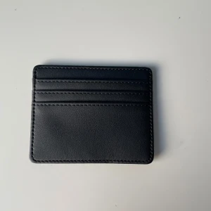 Svart plånbok i skinn - Säljer en stilren och praktisk svart plånbok i skinn. Den har flera kortfack och en enkel design som passar alla tillfällen. Perfekt för att hålla ordning på dina kort och kontanter!