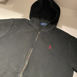 Långärmad Ralph lauren fleece  - Tjena! En väldigt fin Ralph Lauren långärmad hoodie med dragkedja, ca 7/10 i skick. Hoodien är svart. Säljs på grund av att den inte passar längre och inte har blivit använd på länge. Tröjan passar dig om du är mellan 158-168cm lång. Hör av dig om du har några frågor! 