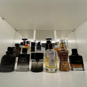 Parfymkollektion med olika märken - En samling av olika parfymer. Märken som syns inkluderar Valentino, Giorgio Armani, Yves Saint Laurent, och Jean Paul Gaultier. 