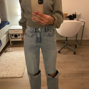Ljusblå jeans med slitningar - Säljer ett par ljusblå jeans från gina tricot. De har en cool, sliten look med stora hål vid knäna. Jeansen har en straight passform. Tror jeans som dessa kommer bli mer eftersökta. Perfekta för tonåringar💖(är 175)
