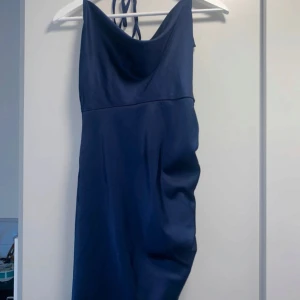 Mörkblå axelbandslös klänning - Snygg mörkblå klänning med axelbandslös design. Perfekt för festliga tillfällen. Klänningen har en elegant passform och är tillverkad i ett mjukt material som ger en fin siluett.