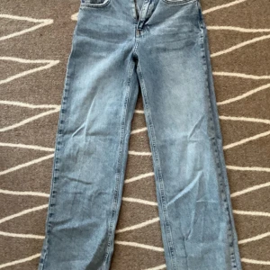 Blå jeans från Gina Tricot - Säljer ett par snygga blå jeans från Gina Tricot. De har en klassisk straight fit och är i en ljusblå tvätt. Jeansen har en fransig detalj vid bensluten som ger en cool och avslappnad look. Perfekta för både vardag och fest!