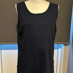 Mörkblå ärmlös topp från Chadar - Säljer en stilren mörkblå ärmlös topp från Chadar. Perfekt för sommardagar eller som ett basplagg i garderoben. Toppen är i storlek L och har en enkel design som gör den lätt att matcha med andra plagg.