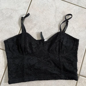 Svart spetslinne från Divided - Säljer ett snyggt svart spetslinne från Divided. Det är axelbandslöst med justerbara band och har en vacker spetsdesign. Perfekt för festliga tillfällen eller en utekväll. Passar bra till både jeans och kjol! skriv vid frågor💗