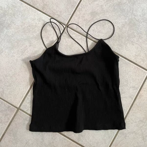 Svart ribbad linne från 157 - Säljer ett svart ribbat linne från 157 i storlek XS/S. Det är ärmlöst med tunna axelband och har en tight passform. Perfekt för sommardagar eller som ett basplagg i garderoben. skriv vid frågor💗