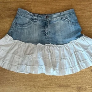 Jeans kjol med volang  - Ljusblå jeanskjol med vita volanger, knappt använd. Strl 38 men passar 36