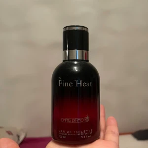 Fine Heat Eau de Toilette från Chris Diamond - Säljer en elegant och stilren Eau de Toilette från Chris Diamond. Flaskan är svart med en röd toning mot botten och har en silverfärgad detalj på korken. Den rymmer 100 ml och är perfekt för både vardag och speciella tillfällen. Doften är fräsch och lite kryddig, perfekt för att göra ett intryck!