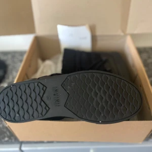 Svarta sneakers från Inuikii - Säljer ett par svarta sneakers från Inuikii. De har en cool design med snörning och en högre krage som ger extra stilpoäng. Perfekta för både vardag och fest!