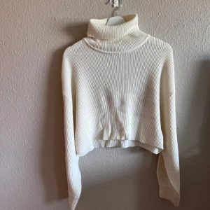Vit ribbad polotröja - Säljer en superfin vit ribbad polotröja som är perfekt för kyliga dagar. Den är croppad och har långa ärmar, vilket ger en trendig look. Tröjan är i nyskick och passar perfekt till både jeans och kjol. Ett måste i garderoben för höst och vinter!