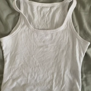 Ribbat linne - Säljer en basic vit ribbad croppad linnetopp. Perfekt för sommardagar eller som ett basplagg i garderoben. Toppen är ärmlös och har en tight passform, storlek M☺️