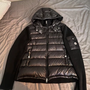 Moncler Cardigan - Moncler hooded tricot cardigan. DEN är i bra skick men har några ”loppor” på armen asså där det stickade tyget har hoppat ut lite men inget som märks alls. Den är köpt på Wallenbergs i Sundsvall för något år sedan. Pris diskuterbart vid smidig affär.