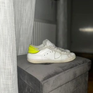 Philippe model skor  - Snygga vita sneakers med en iögonfallande gul detalj på hälen. Skorna har klassisk snörning och en stilren design som passar perfekt för en avslappnad look. Priset kan diskuteras 